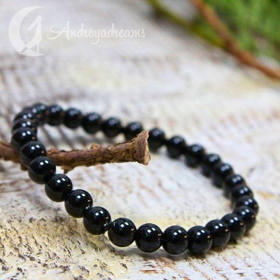 Pulseira de contas pretas brilhantes sobre superfície clara texturizada