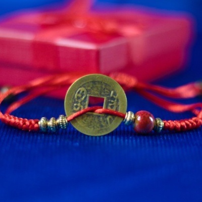 Pulseira vermelha com moeda chinesa dourada e conta, caixa de presente vermelha ao fundo