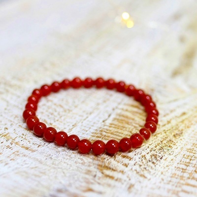 Pulseira de contas vermelhas sobre superfície de madeira clara