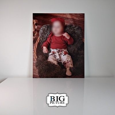 Fotografia de bebé vestida de vermelho e branco numa moldura sobre superfície branca