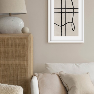 Sala com sofá, almofadas, candeeiro, aparador e quadro abstrato na parede