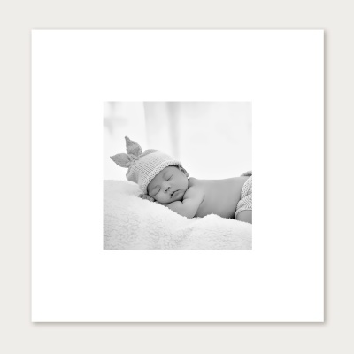 Bebé a dormir deitado sobre manta branca com touca e braguilha de tricot