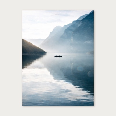 Lago calmo com montanhas e duas pessoas numa pequena embarcação