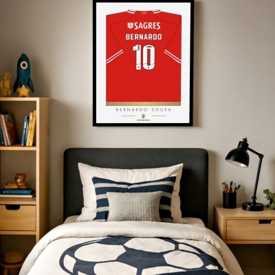 Quarto com cama, roupa de cama com padrão de bola de futebol e poster de camisola vermelha de futebol na parede.