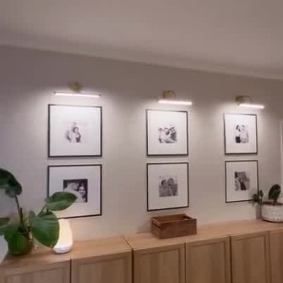 Quadros decorativos iluminados por luzes LED em parede branca com móveis de madeira