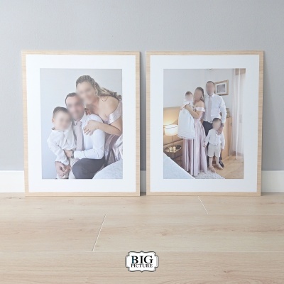 Duas molduras de madeira clara com fotos de família apoiadas no chão
