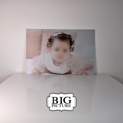 Fotografia impressa de bebé em vestido branco sobre superfície branca brilhante