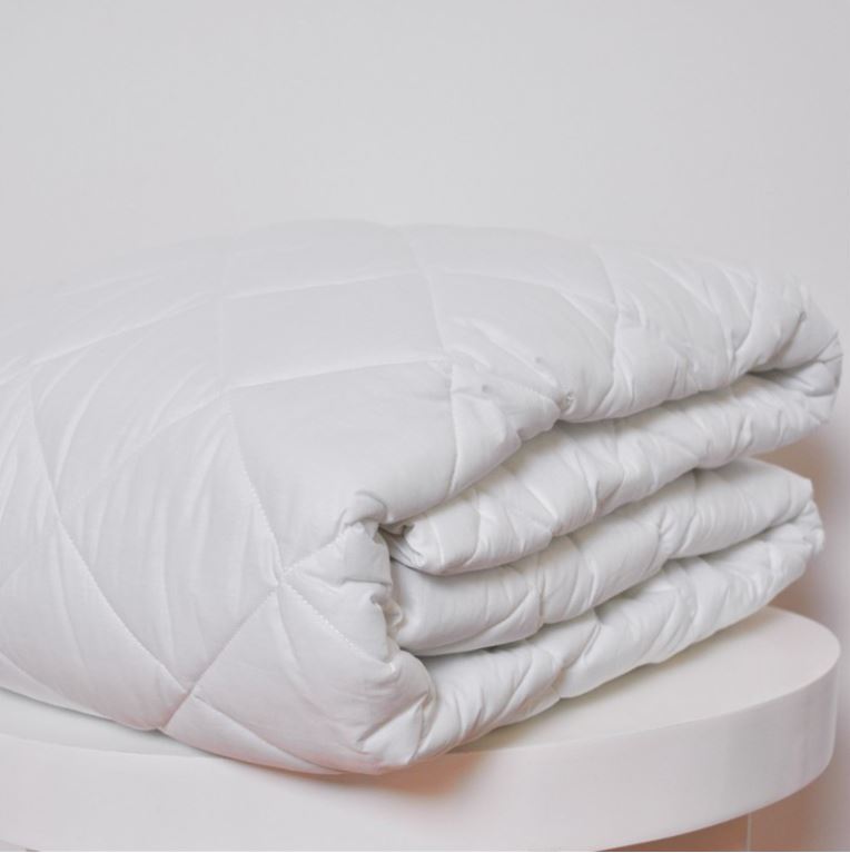Edredão branco matelassê dobrado em superfície branca
