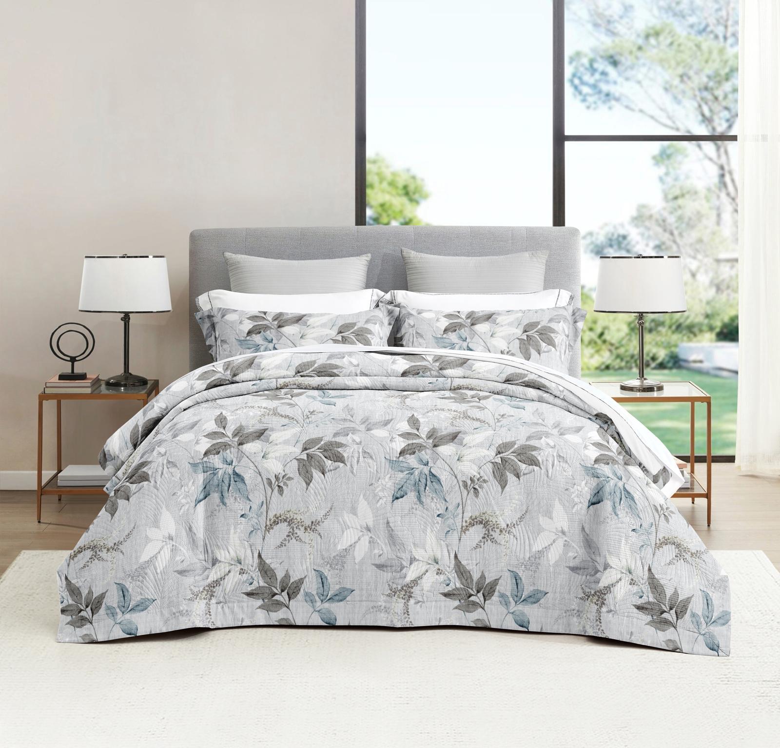 Roupa de cama com padrão floral cinza e azul num quarto moderno e iluminado