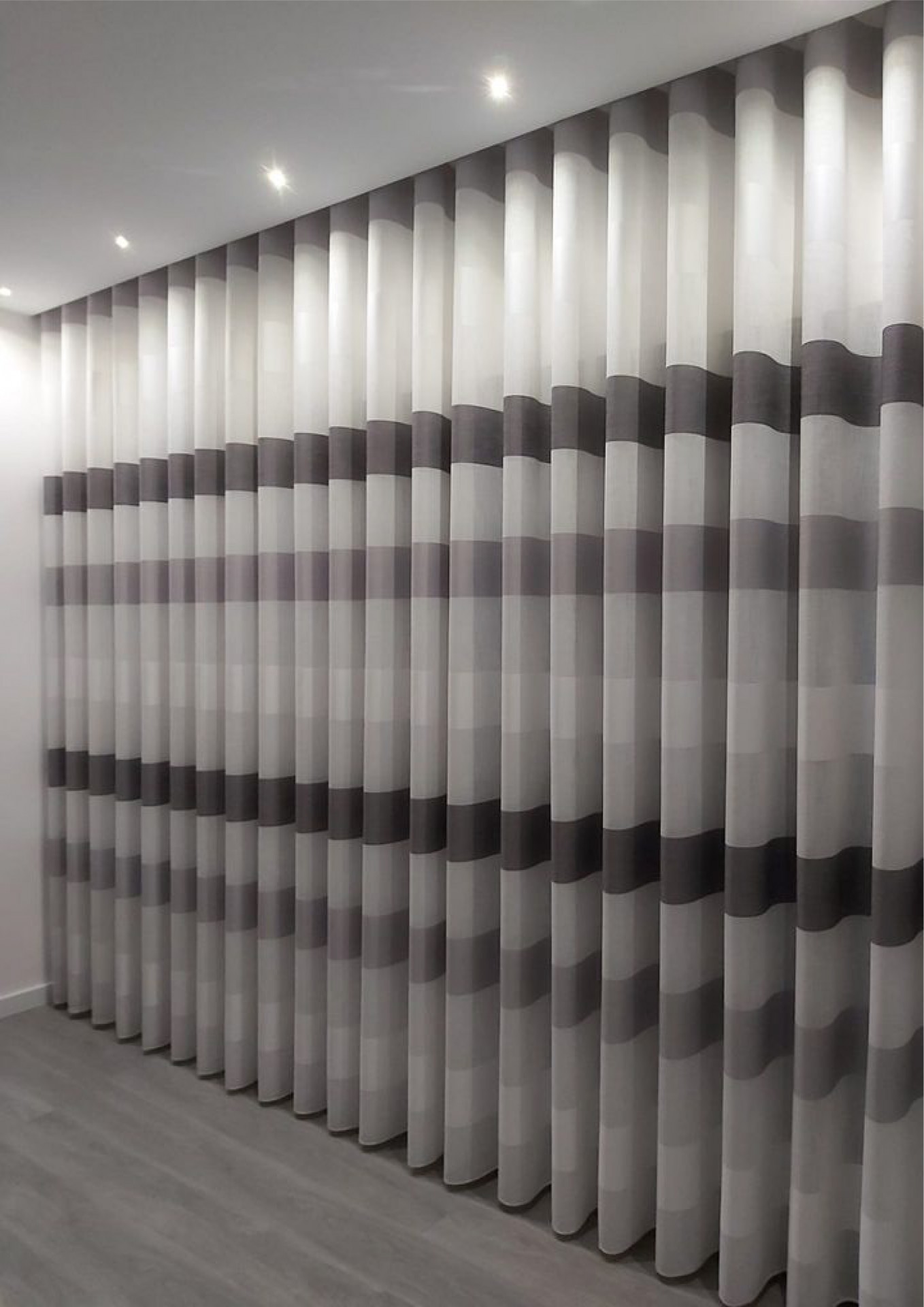 Cortinas em tecido listrado cinza numa sala moderna com chão cinza e iluminação no teto