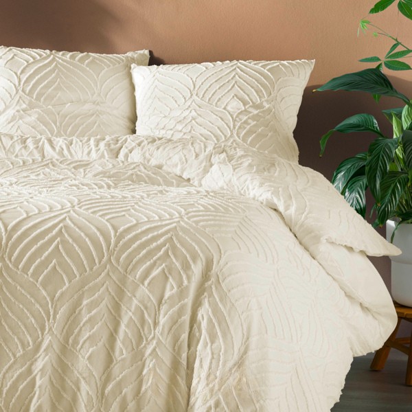 Roupa de cama creme com padrão em relevo, edredão e almofadas numa cama