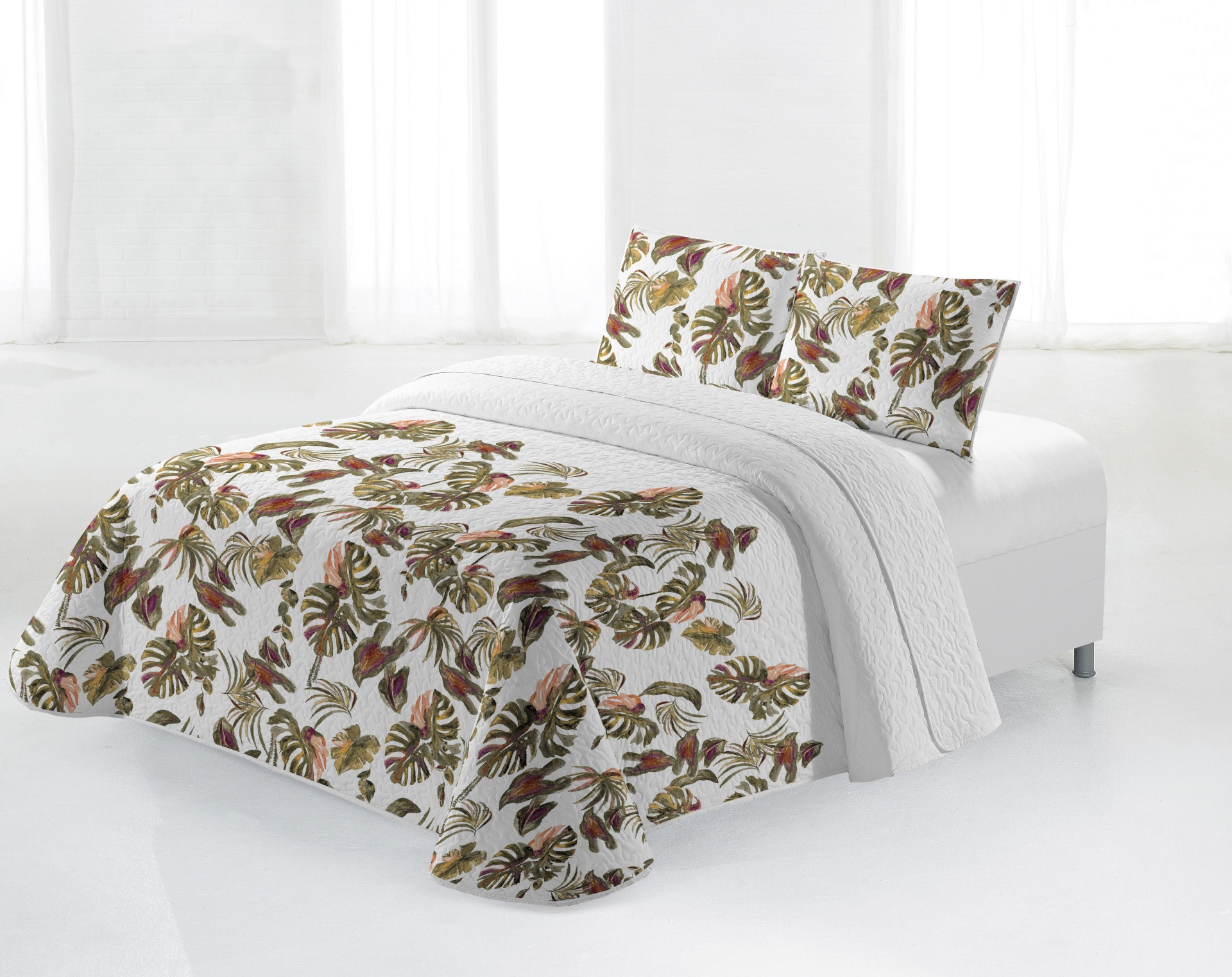 Colcha com padrão de folhas tropicais e almofadas combinando num cenário branco minimalista