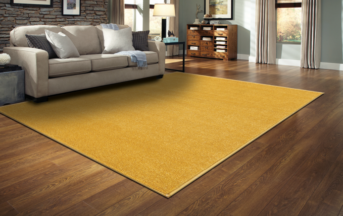 Tapete amarelo retangular numa sala com sofá cinzento e chão de madeira