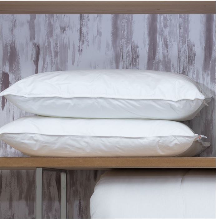 Dois almofadas brancas empilhadas numa prateleira de madeira com parede cinza ao fundo