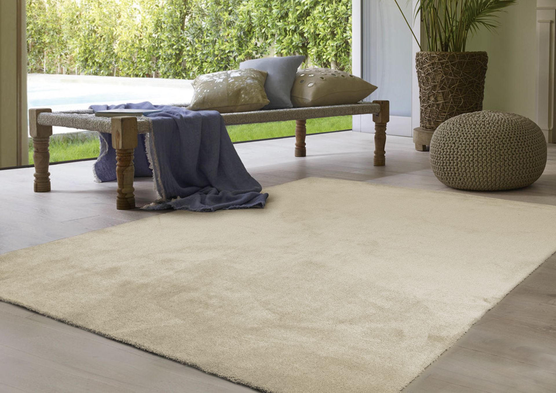 Almofadão bege retangular numa sala clara ao lado de banco de madeira e pufe de crochê