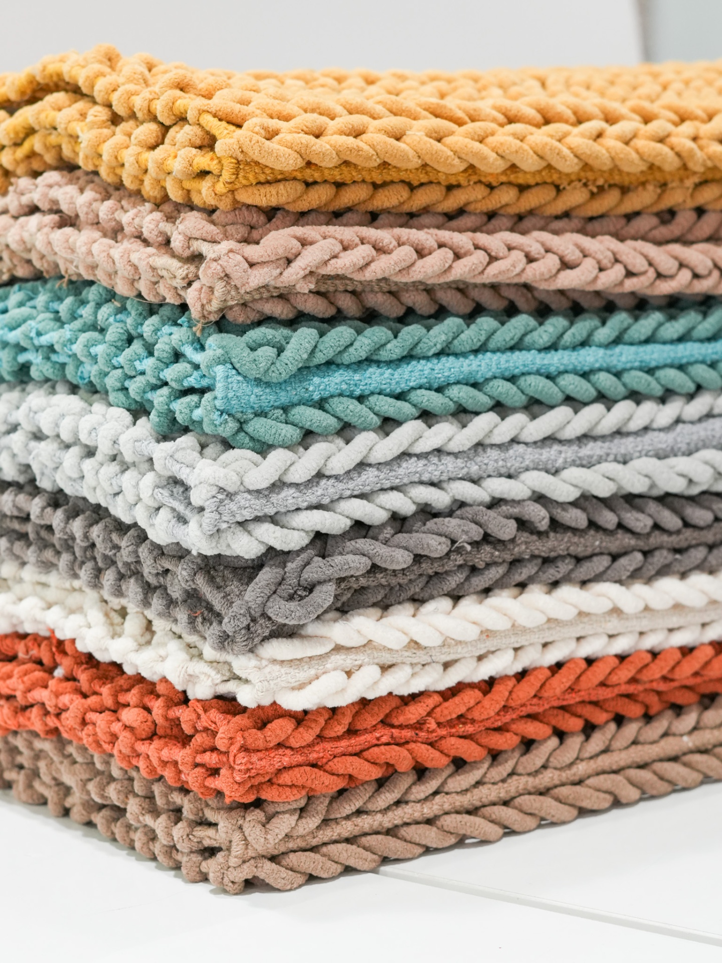 Empilhamento de mantas decorativas de várias cores com textura trançada