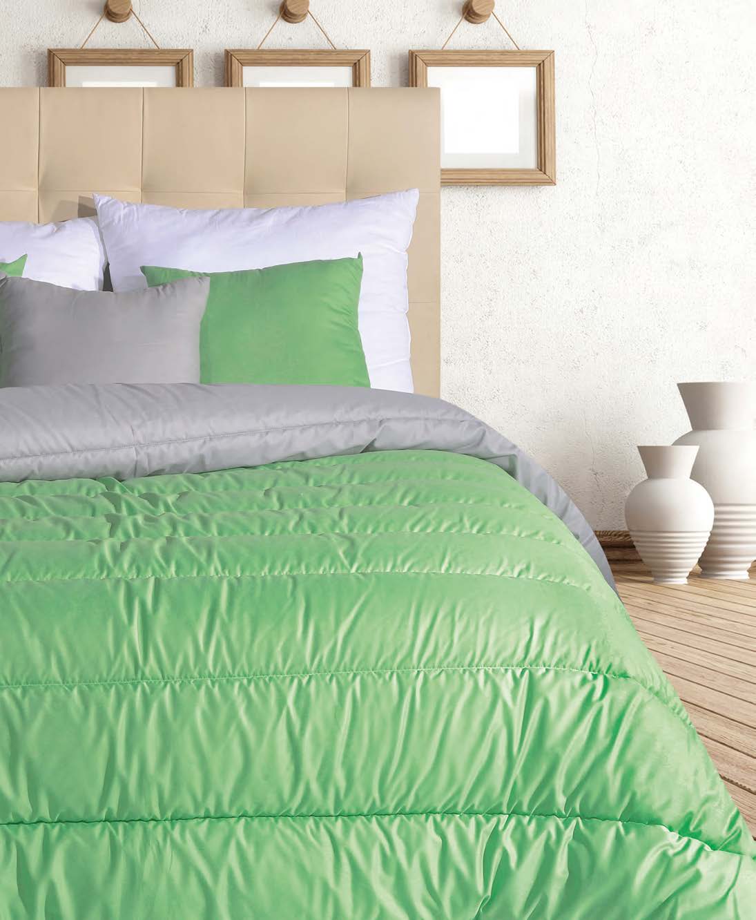 Cama com edredão verde, almofadas mistas e cabeceira bege