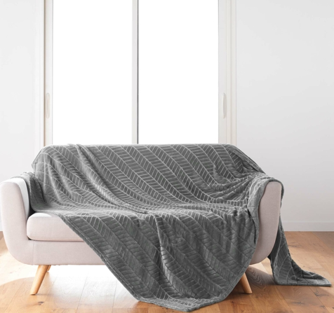 Manta cinza com padrão geométrico sobre sofá cinzento claro