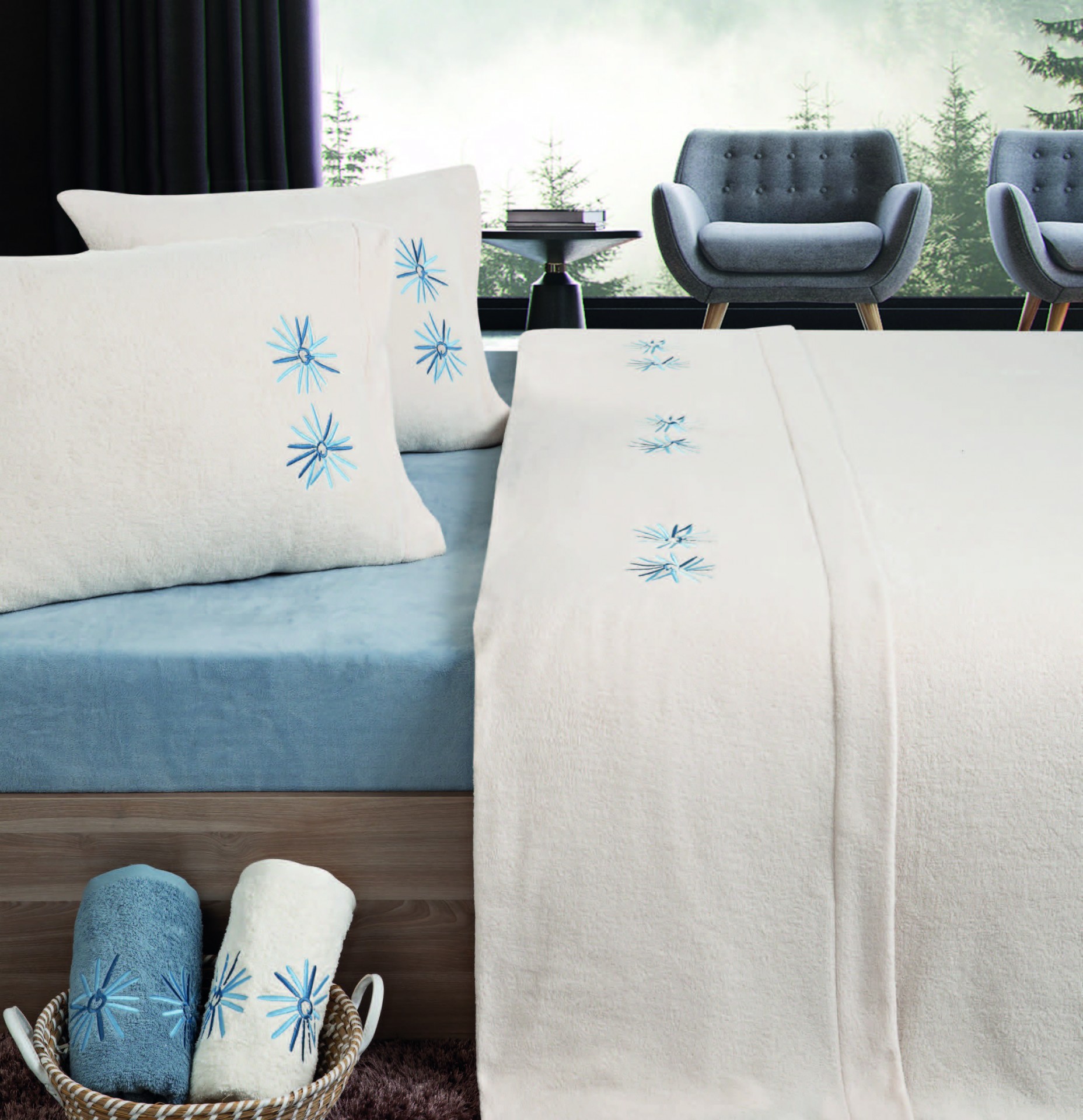 Roupa de cama branca com bordados azuis sobre lençol azul numa cama, com poltronas cinza ao fundo