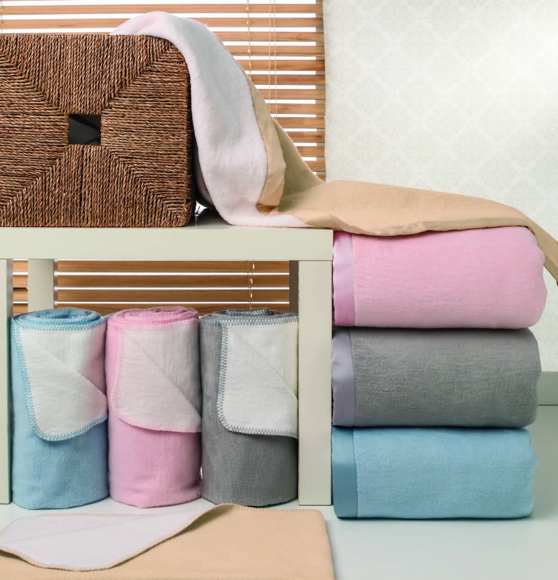 Mantas ou toalhas coloridas dobradas e enroladas sobre mesa branca com cesto decorativo