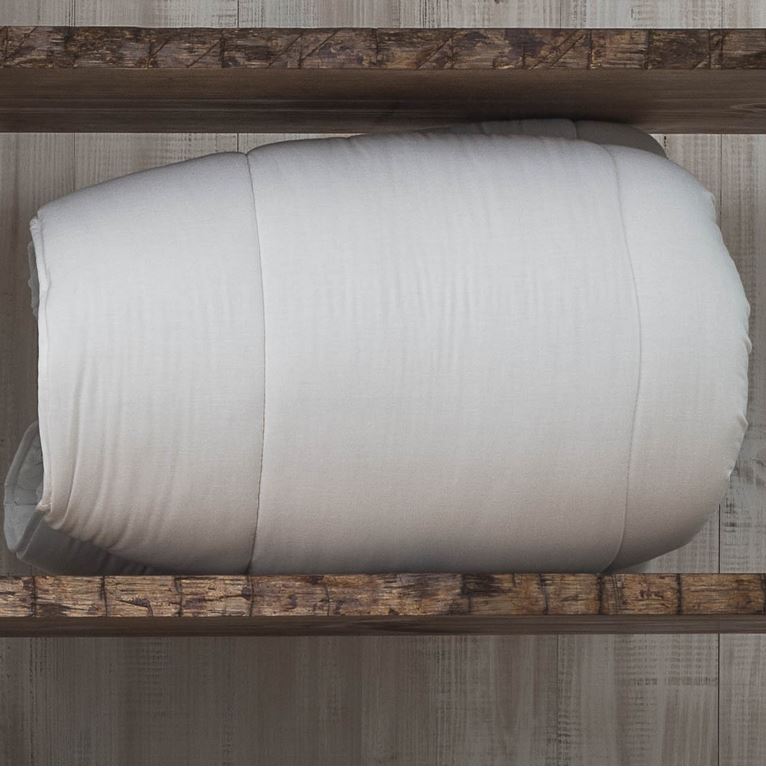 Edredão branco enrolado numa prateleira de madeira rústica
