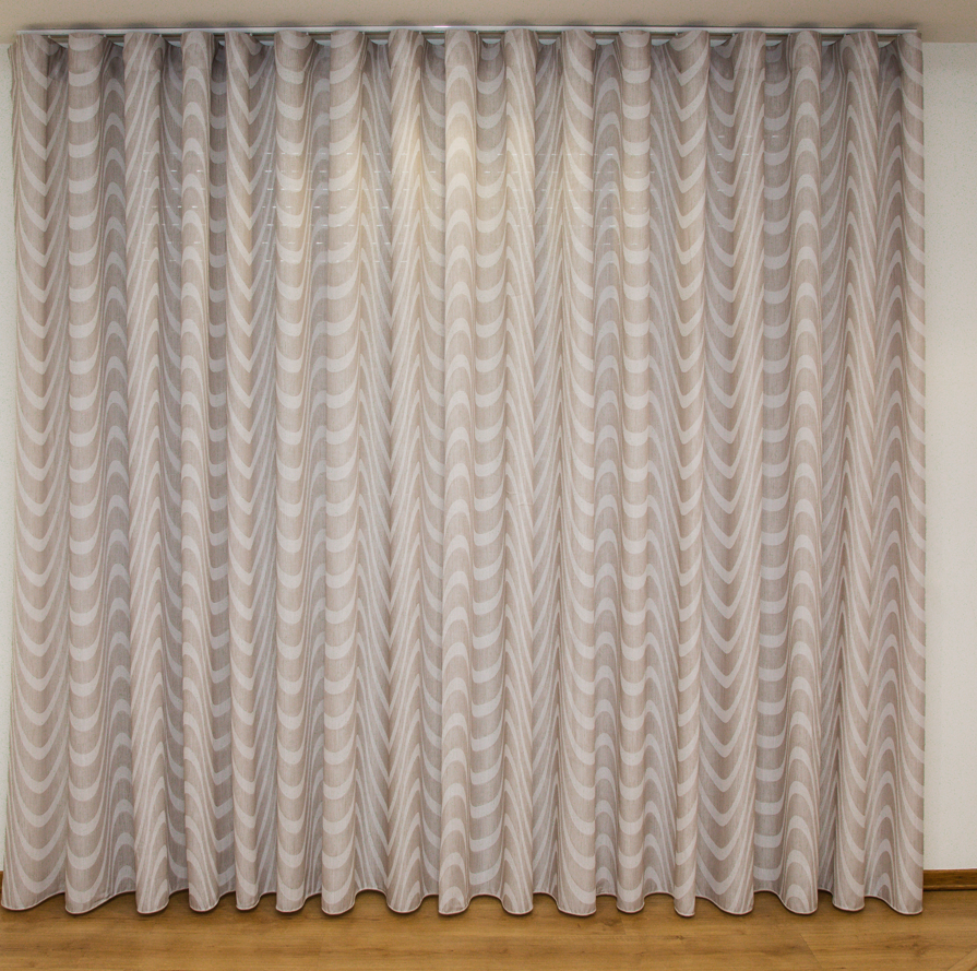 Cortina bege com padrão ondulado pendurada em parede branca e chão de madeira