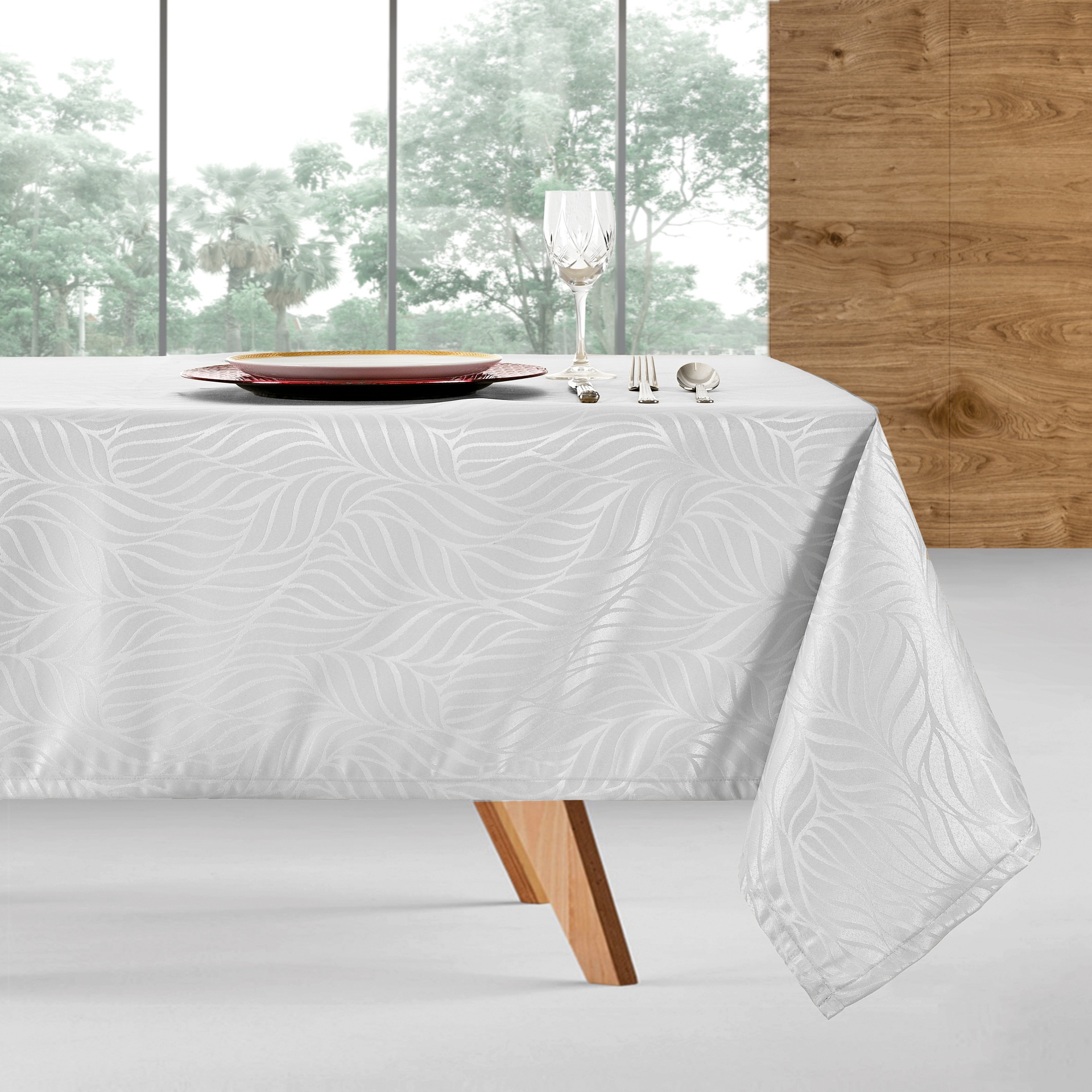 Toalha de mesa branca com padrão de folhas texturizadas numa mesa de madeira clara