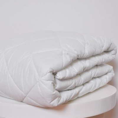 Edredão branco matelassê dobrado em superfície branca