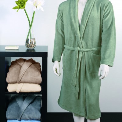 Roupão de banho verde claro em manequim ao lado de estante com roupões dobrados e vaso com flores