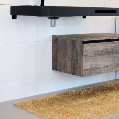 Móvel suspenso em madeira clara com gaveta, loiça preta acima e tapete castanho claro sobre chão cinzento