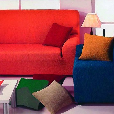 Dois sofás coloridos, uma mesa branca com objetos e uma lâmpada de mesa.