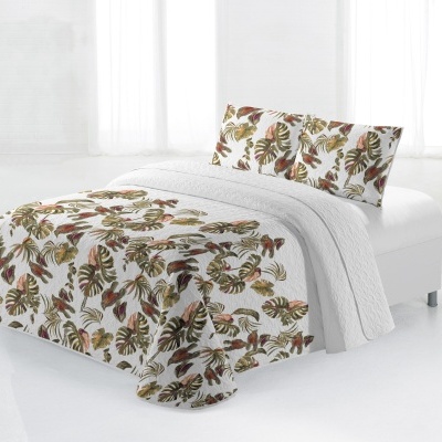 Colcha com padrão de folhas tropicais e almofadas combinando num cenário branco minimalista