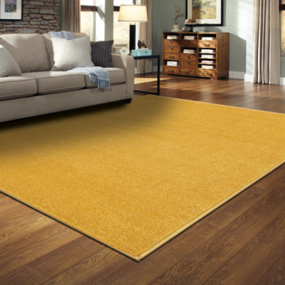 Tapete amarelo retangular numa sala com sofá cinzento e chão de madeira