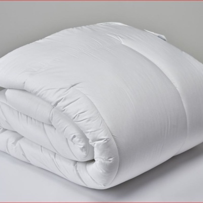 Edredão branco dobrado sobre superfície branca