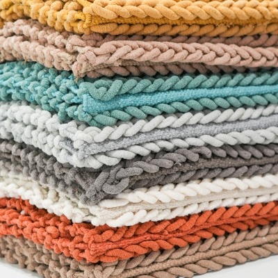 Empilhamento de mantas decorativas de várias cores com textura trançada