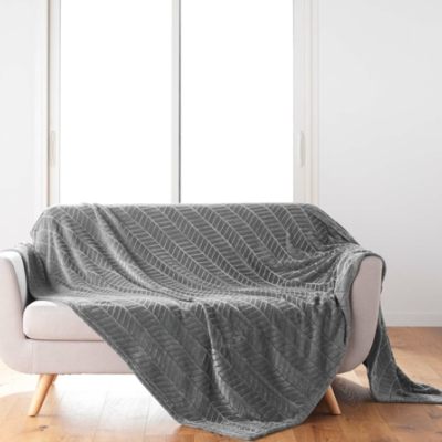 Manta cinza com padrão geométrico sobre sofá cinzento claro