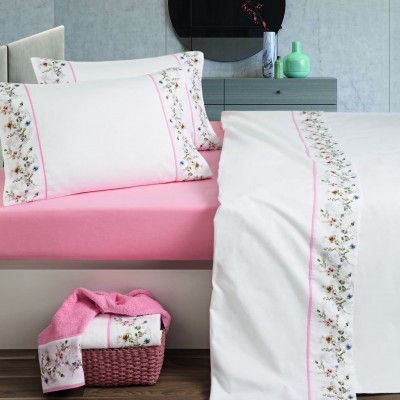 Jogo de cama branco com bordado floral e lençol rosa em quarto moderno