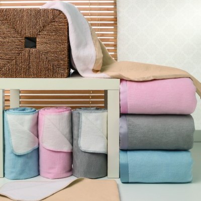 Mantas ou toalhas coloridas dobradas e enroladas sobre mesa branca com cesto decorativo