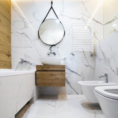 Casa de banho moderna com sanitários brancos, lavatório com móvel madeira e espelho redondo