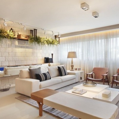 Sala de estar moderna com sofá branco, cadeiras de madeira castanha, mesa e banco, parede cinza com plantas