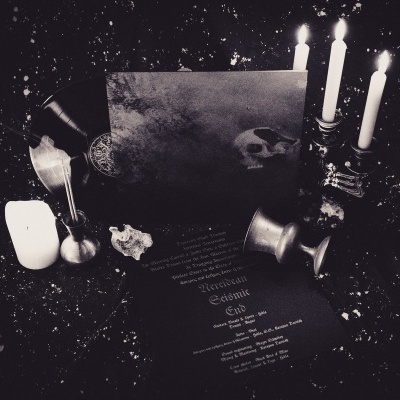 Conjunto de objetos em ambiente escuro com velas, papel com crânio desenhado e texto em francês.