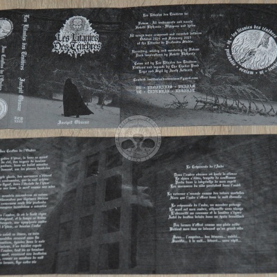 Capa de álbum preto e cinzento com texto branco e figura encapuzada