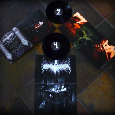 Dois discos de vinil com capas escuras e pôster artístico sobre chão escuro