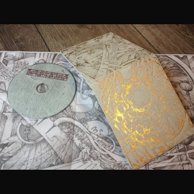 CD com embalagem cinzenta e dourada com padrões complexos