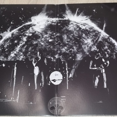 Banda a atuar ao vivo em palco com instrumentos e projeção gráfica