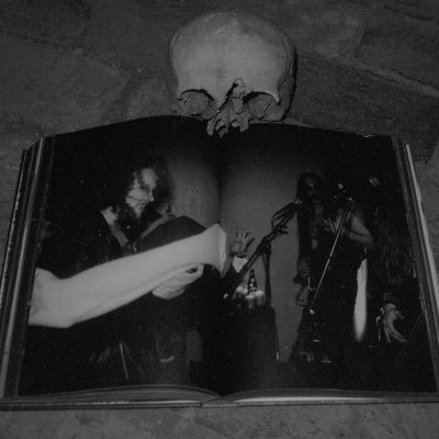 Livro aberto com fotografia em preto e branco de músicos em palco e crânio em cima