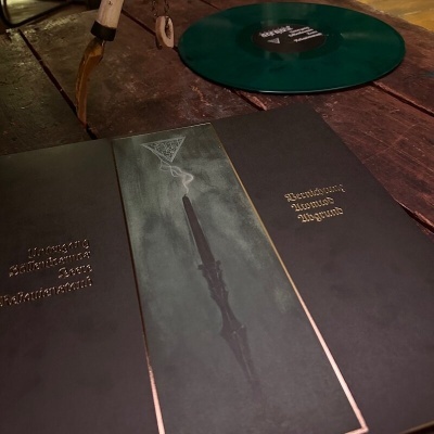 Capas de álbuns de vinil e disco verde escuro sobre mesa de madeira
