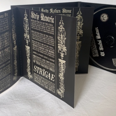 Embalagem de CD preta com texto e decoração dourada, CD dentro e livreto aberto com informações.