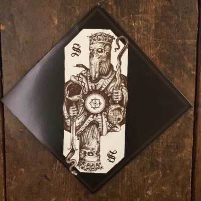 Lenço preto com desenho de rei e letras S, sobre madeira escura