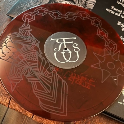 Disco de vinil vermelho translúcido com gravuras de corrente e mão segurando maçã